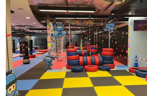 The NinjaGym venue: climbing walls, tire obstacles and the blue ninja mascot everywhere